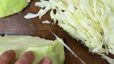 Bir aşçı, ahşap kesme tahtasındaki bıçakla lahana keser..