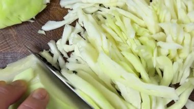 Bir aşçı, ahşap kesme tahtasındaki bıçakla lahana keser..