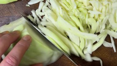 Bir aşçı, ahşap kesme tahtasındaki bıçakla lahana keser..