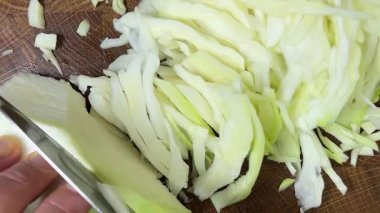 Bir aşçı, ahşap kesme tahtasındaki bıçakla lahana keser..