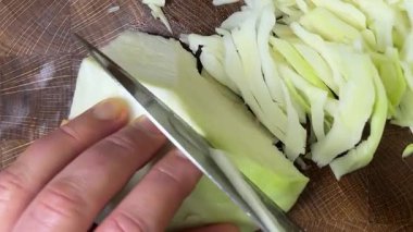 Bir aşçı, ahşap kesme tahtasındaki bıçakla lahana keser..