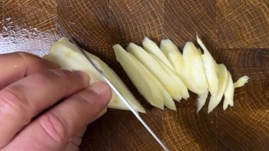 Bir aşçı, ağaç kesme tahtasına saplanmış bir bıçakla maydanoz kökü doğruyor..