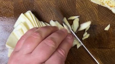 Bir aşçı, ağaç kesme tahtasına saplanmış bir bıçakla maydanoz kökü doğruyor..