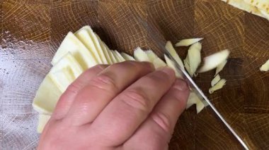 Bir aşçı, ağaç kesme tahtasına saplanmış bir bıçakla maydanoz kökü doğruyor..