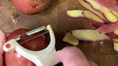 Ahşap kesim tahtasında patates soyan kadın..