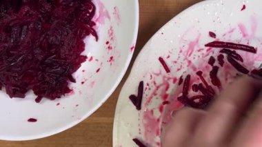 Beyaz tabak arka planında rendelenmiş pancar rendeleniyor.