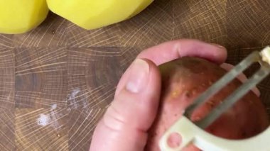 Ahşap kesim tahtasında patates soyan kadın..