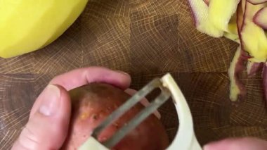 Ahşap kesim tahtasında patates soyan kadın..