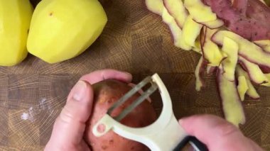 Ahşap kesim tahtasında patates soyan kadın..