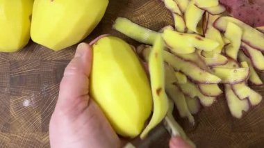 Ahşap kesim tahtasında patates soyan kadın..