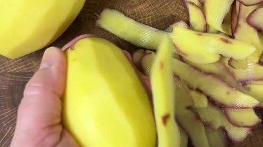 Ahşap kesim tahtasında patates soyan kadın..