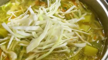 Patates ve havuçla dolu bir tencereye doğranmış lahana ekliyorum. Ukrayna borsası yapma süreci.