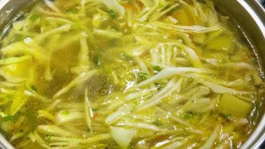 Patates, havuç ve lahana dolu bir kaba doğranmış pırasa sapı eklemek. Ukrayna borsası yapma süreci.