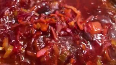 Bir aşçı Ukrayna borşunu kaşıkla tencerede karıştırır. Borş yapma süreci.