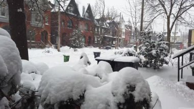 Toronto, Ontario, Kanada 'da karlı bir kış. Karlı ön bahçeden, yerleşim alanındaki iki katlı tuğladan özel evlere ve kar yağarken yavaşça geçen arabaya bakın..