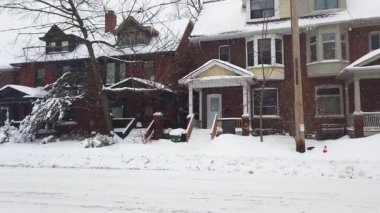 Toronto, Ontario, Kanada 'da karlı bir kış. İki katlı tuğlalı özel evler, ıssız bir cadde ve kar yağarken yavaşça geçen bir araba..
