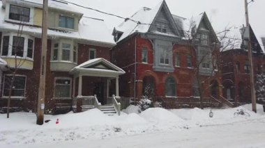 Toronto, Ontario, Kanada 'da karlı bir kış. İki katlı tuğlalı özel evler, ıssız bir cadde ve kar yağarken yavaşça geçen bir araba..