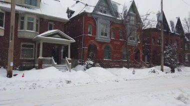 Toronto, Ontario, Kanada 'da karlı bir kış. İki katlı tuğlalı özel evler, ıssız bir cadde ve kar yağarken yavaşça geçen bir araba..