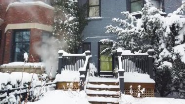 Toronto, Ontario, Kanada 'da karlı bir kış. Verandası ve verandası karla kaplı iki katlı tuğladan ev manzarası. Isıtma sisteminden çıkan buhar evin bodrumundan yükseliyor..