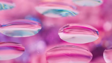 Pembe, mavi ve mor tonlarda soyut bir arka plan. Çiçeklerin tonlarını değiştiren cam damlaları.