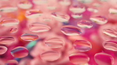 Pembe ve mavi tonlarda soyut bir arka plan. Çiçeklerin tonlarını değiştiren cam damlaları.