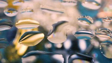 Gri mavi tonlarda, kristal ve altın parıltılarıyla soyut arkaplan. Camın üzerindeki damlalarda renklerin tonları değişiyor.