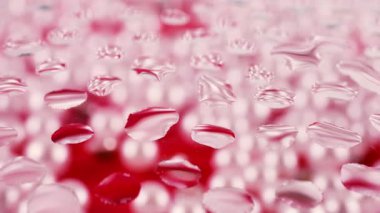 İnci ve kırmızı tonlarda soyut bir arkaplan. Camın üzerindeki damlalarda renklerin tonları değişiyor.