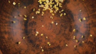 Bulgur Groats kahverengi bir seramik kaseye dökülür. Üst Manzara. Yavaş çekim.