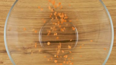 Mercimek tohumları cam bir kaseye, tahta bir meşe ağacına dökülüyor. Üst Manzara. Yavaş çekim.