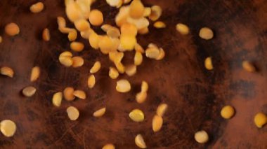 Kurutulmuş bezelyeler kahverengi bir seramik kaseye dökülür. Üst Manzara. Yavaş çekim.