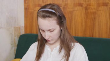 Genç bir kız restoranda bir masada oturuyor ve akıllı telefondan mesaj yazıyor..