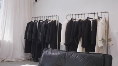 Mağazadaki bir elbise koleksiyonu beyaz bir duvara asılmış..