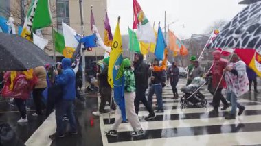 TORONTO, CanADA - 17 Mart 2025: Toronto, Ontario, Kanada 'da Aziz Patrick Günü geçit töreni. Çeşitli renkte bayraklar taşıyan bir grup insan yağmurda bir geçit törenine katılıyor..
