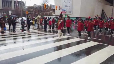 TORONTO, Kanada - 17 Mart 2025: Toronto, Ontario, Kanada 'da Aziz Patrick Günü Geçidi. Bir tören sırasında, parlak kırmızı üniformalı bir pirinç ve perküsyon grubu yürür..