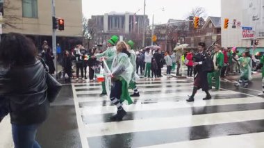 TORONTO, Kanada - 17 Mart 2025: Toronto, Ontario, Kanada 'da Aziz Patrick Günü Geçidi. Parlak yeşil ve beyaz takım elbiseli ve gayda çalan bir müzisyen eşliğinde Öngörü Başarı Şirketi temsilcileri.