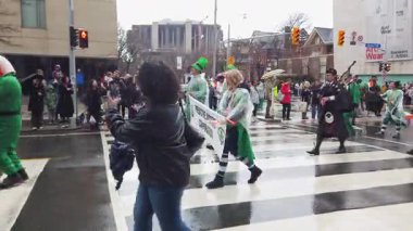 TORONTO, Kanada - 17 Mart 2025: Toronto, Ontario, Kanada 'da Aziz Patrick Günü Geçidi. Parlak yeşil ve beyaz takım elbiseli ve gayda çalan bir müzisyen eşliğinde Öngörü Başarı Şirketi temsilcileri.
