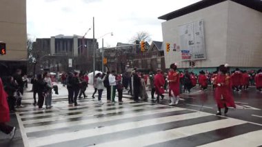 TORONTO, Kanada - 17 Mart 2025: Toronto, Ontario, Kanada 'da Aziz Patrick Günü Geçidi. Bir tören sırasında, parlak kırmızı üniformalı bir pirinç ve perküsyon grubu yürür..