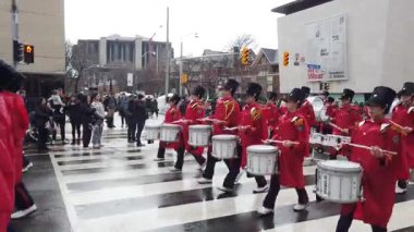 TORONTO, Kanada - 17 Mart 2025: Toronto, Ontario, Kanada 'da Aziz Patrick Günü Geçidi. Bir tören sırasında, parlak kırmızı üniformalı bir pirinç ve perküsyon grubu yürür..