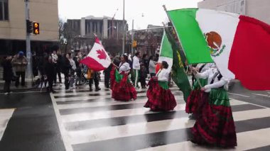 TORONTO, CANADA - 17 Mart 2025: Beyaz gömlekli, kırmızı ve yeşil etekli, ellerinde Kanada ve İrlanda bayrakları olan bir grup güzel kız geçit törenine katılıyor.
