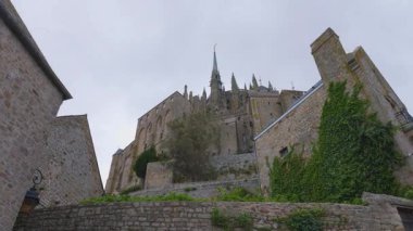 Mont-Saint-Michel Manastırı 'nın mavi gökyüzüne ve rüzgarlı bir bahar gününde bulutlara bakan manzarası. Mont-Saint-Michel Abbey, Manche ilinin Mont-Saint-Michel ilçesinde yer alan bir manastır..