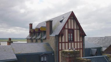 # Mont-Saint-Michel Manastırı 'nın duvarlarından # # Yarı ahşap bir evin dış cephesinde # # ve rüzgarlı bir bahar gününde kiremitli çatılarda #.