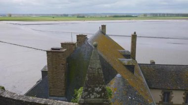 Mont-Saint-Michel Manastırı 'nın duvarlarından eski binaların ve Manş Denizi' nin kiremitli çatılarının üzerinden rüzgarlı bir bahar gününde.