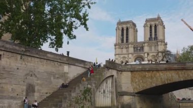 Turistli bir yolcu gemisi Petit Pont köprüsünün altından geçiyor Kardinal Lustiger Seine Nehri üzerinde. Notre-Dame de Paris manzarası ve Seine Nehri 'nin setinde dinlenen insanlar. 4. Bölge, Paris, Fransa.