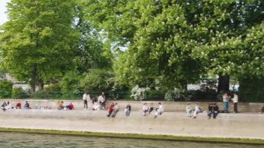 Sen nehri kıyısında bir tekne gezisi. Vert-Galant Meydanı manzarası, Seine Nehri 'nin setinde dinlenen insanlar, Pont Neuf köprüsü ve Henri IV Binicilik Heykeli, Cite Adası, 4. bölge, Paris, Fransa.