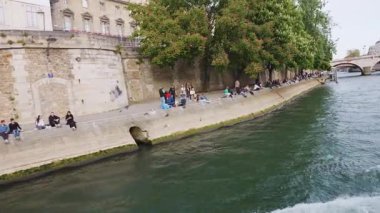 Sen nehri kıyısında bir tekne gezisi. Çiçekli kestane ağaçlarının manzarası, Quai des Orfevres seti üzerinde dinlenen insanlar, Parquet du Tribunal de Orfevres (36 Quai des Orfevres) ve Pont Saint-Michel, 4. bölge, Paris, Fransa.