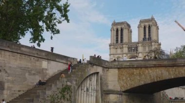PARIS, FRANCE - 21 Nisan 2025: Turistlerle dolu bir yolcu gemisi Petit Pont köprüsünün altından geçiyor - Kardinal Lustiger Seine Nehri üzerinde. Notre-Dame de Paris manzarası, nehir, rıhtım ve güvertede turistler. 4. bölge, Paris..