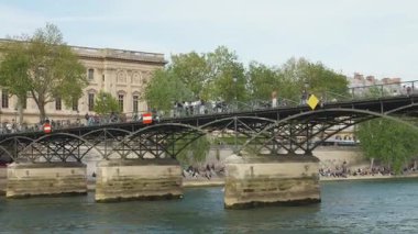 PARIS, FRANCE - 21 NİSAN 2025: Seine Nehri manzarası, kemer çeliği Pont des Arts, Institut de France ve turistler 1. arrondissement, Paris 'teki toprak ve köprü boyunca yürüyorlar..