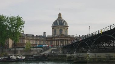 PARIS, FRANCE - 21 NİSAN 2025: Seine Nehri manzarası, toprak seti, yaya köprüsü Pont des Arts, Institut de France ve demirlemiş tekneler..