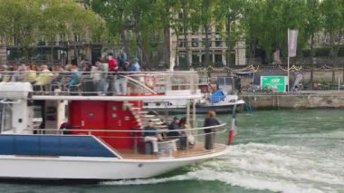 PARIS, FRANCE - 21 NİSAN 2025: Seine Nehri manzarası, koşan, demir atmış tekneler, geçen motorlu tekneler ve turistlerle dolu bir gemi..
