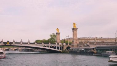 PARIS, FRANCE - 21 NİSAN 2025: Seine Nehri manzarası, tek kemerli köprü Pont Alexandre III, turistlerle dolu büyük bir çift güverte gemisi günbatımı gökyüzünün arka planına doğru yelken açıyor..